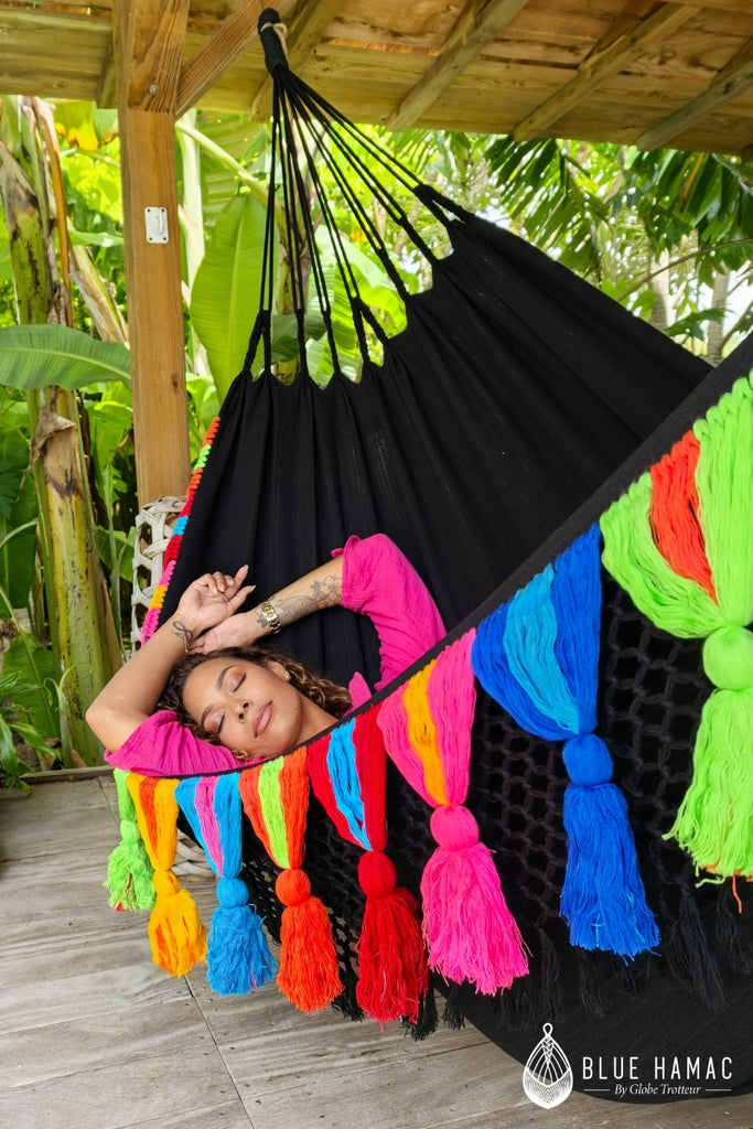 hamac noir avec des franges et pompons multicolores large elegant et confortable mathilda crampon dans le hamac sous une terrasse couverte en guadeloupe endormie