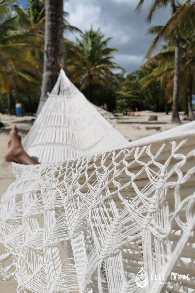 hamac blanc en macramé tissé au brésil en coton il est idéal pour une sieste quotidienne plage assis dans un hamac ciel bleu lagon detail franges